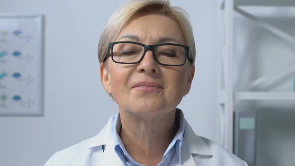 Friendly Female Doctor Putting on Beige and Smiling to Camera, Appointment