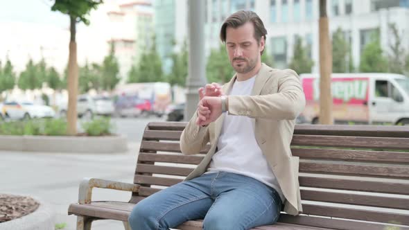 Outdoor Young Man Using Smartwatch While Sitting on Bench