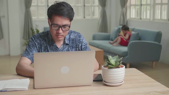 Asian Man Working With Laptop Computer And Son Use Mobile Phone