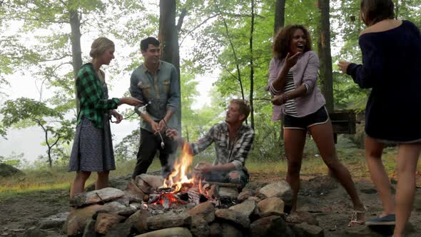 Friends toasting marshmallows over campfire in forest