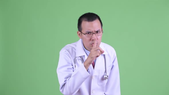 Stressed Asian Man Doctor with Finger on Lips