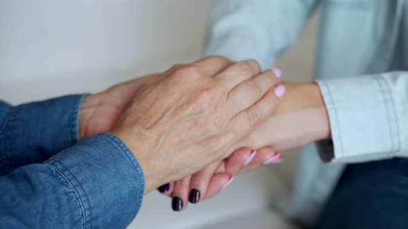 The Hands of an Elderly Woman Touch the Hands of a Young Woman