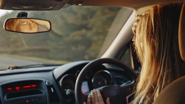 Rear View of Happy Young Blonde in Stylish Sunglasses Dancing to the Music While Driving Her Car at