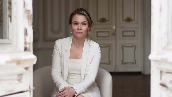 an Attractive Blonde Woman in a White Suit in Rooms with Classic White Interior