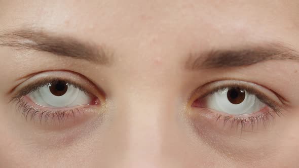 Closeup of a Browneyed Young Woman Wearing the White Decorative Lenses Opening Eyes and Closing