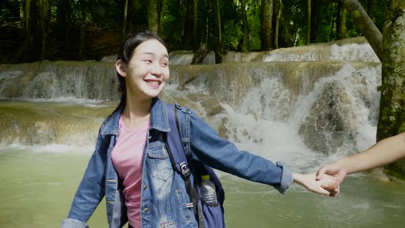 Asian Girl Holding Her Boyfriend’s Hand And Walking In Waterfall