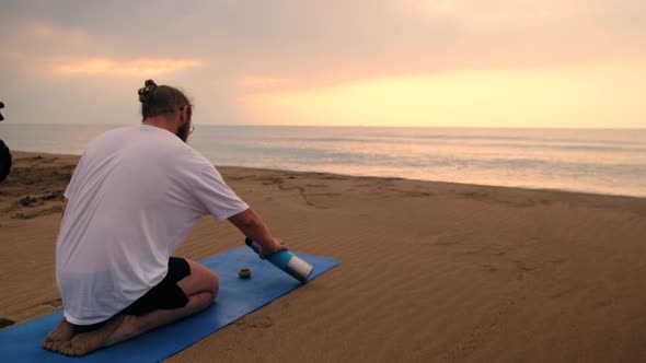 Man Drinks Tea at Beach