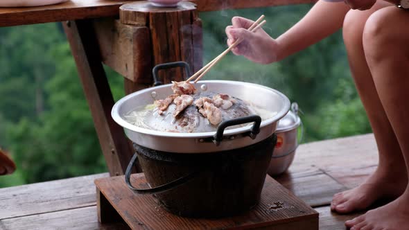 People cooking and eating Moo Kata, Thai barbecue grill pork on circle hot pan