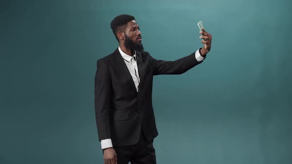 A Pretty African Man with a Dark Beard in a White Shirt and Black Suit is Taking Some Photos on His