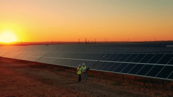 Aerial Shot of Solar Energy Engineers on a Solar Farm at Sunset