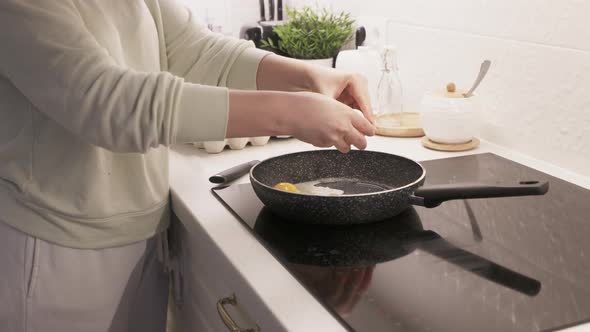 Woman Cooking Scrambled Eggs on Electric Stove Top in the Kitchen Frying Pan with Fried Eggs on