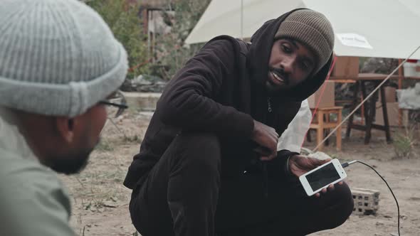 Refugee Men Using Mobile Phones at Tent City