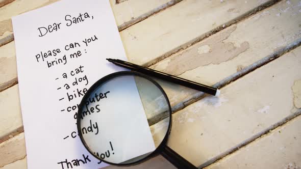 Letter to santa claus with magnifying glass and pen on a wooden plank