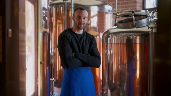 Confident Brewer Crossing Hands Looking at Camera Standing in Brewery Indoors