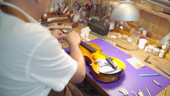 Craftsman assembling bow on violin