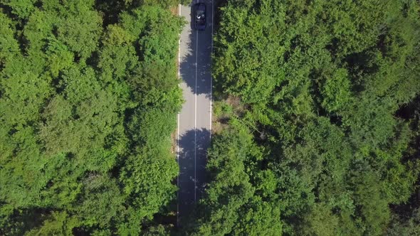 Aerial View Flying Over Old Patched Two Lane Forest Road With Cars