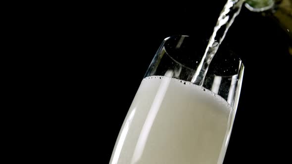 Champagne being poured in glass against black background