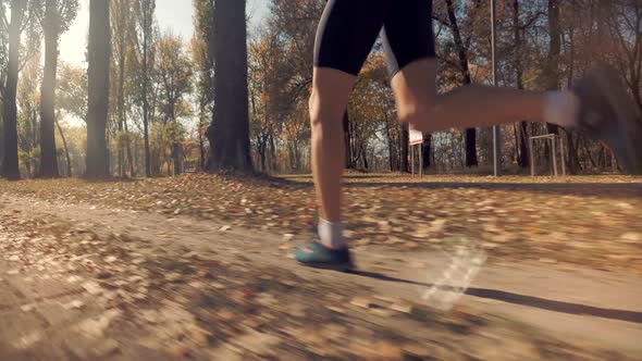 Runner Man Fit Athlete Legs Jogging On Trail Ready To Triathlon. Running Man In Forest At Sunset.