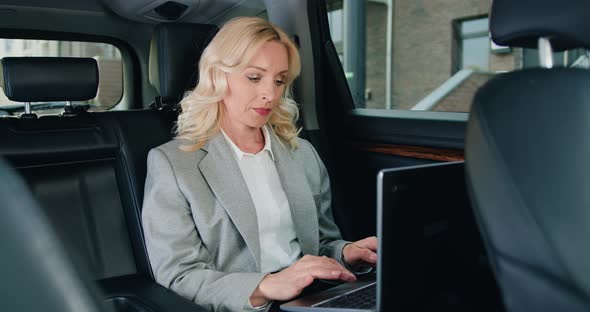 Woman Sitting on Back Seat of Car Using Laptop