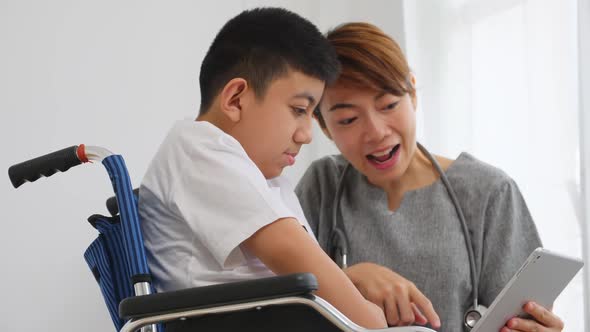 A physical therapist is taking care to a disabled boy in a wheelchair.