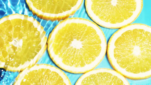 Macro Orange Fruit Slices and Blue Water Surface Texture with Ripple and Splash