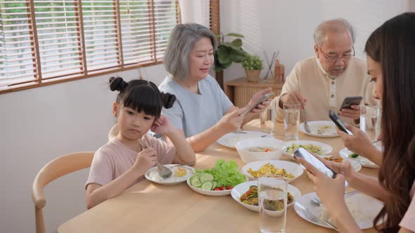 Asian Ignoring Family,  addicted parents not paying attention on small child while eating in house.