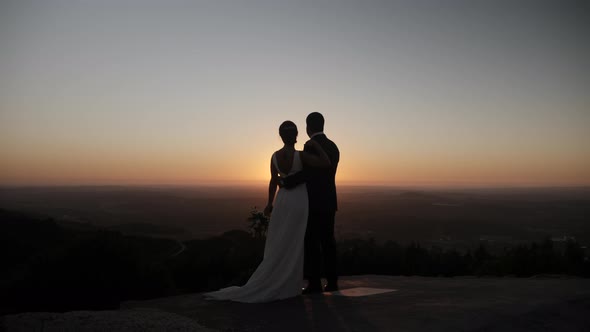 Zoom out of a fresh married couple in the sunset