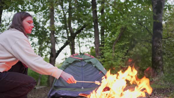 A Beautiful Woman Burn Marshmallows on a Campfire in a Camp