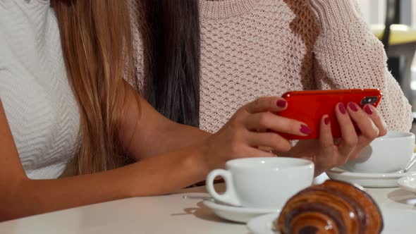 Beautiful Female Friends Using Smart Phone at the Coffee Shop Together