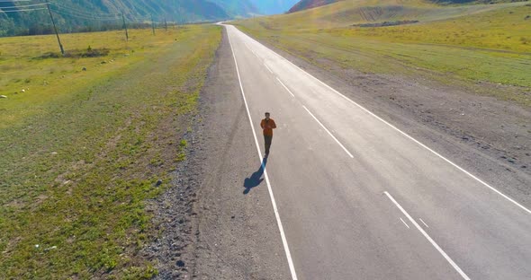 Low Altitude Flight in Front of Sporty Man at Perfect Asphalt Road