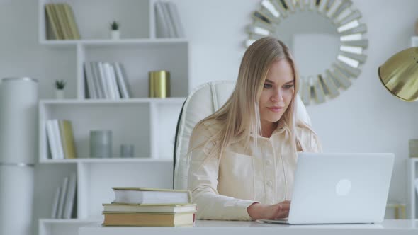 Smiling girl receiving good news at the desk in home office