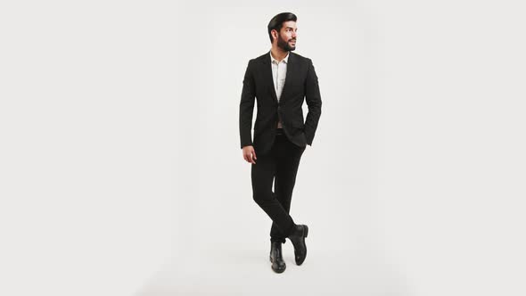 Sexy Bearded Cuban Guy in a Black Expensive Suit Pointing with His Finger in Copy Space Smiling