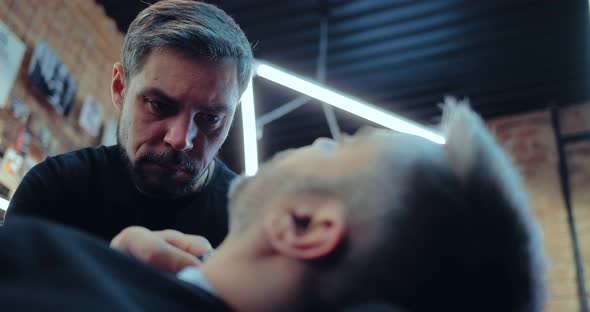 Professional Barber Cuts the Beard to the Client
