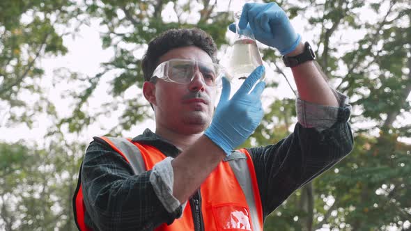 Biological engineer and assistants collecting samples of factory wastewater in a test tube