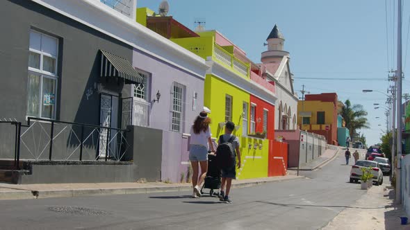 Woman Walking with Son and Baby Stroller in the Streets of Colorful Buildings Neighbourhood BoKaap