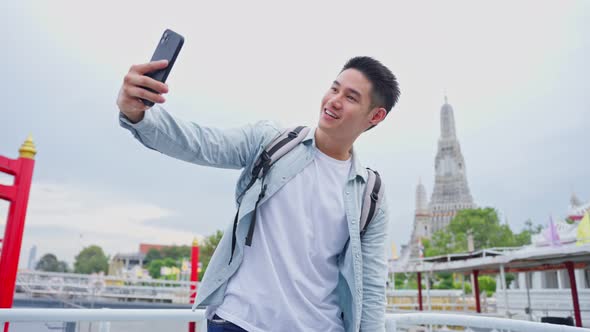 Asian man backpacker using mobile phone take picture of Buddha temple.