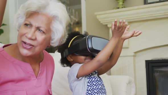 Happy african american grandmother with granddaughters using vr headset in living room