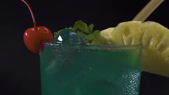 A Glass Green Cocktail Drink Rotating on Black Background. Close Up Shot.