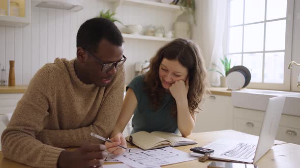 Multinational Couple Discuss Apartment Layout at Table