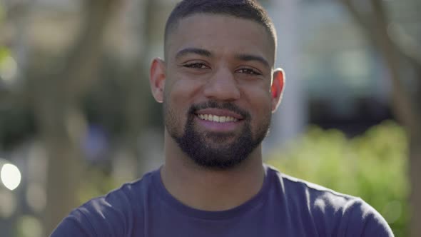 Closeup of Young Man in Park Looking at Camera, Smiling