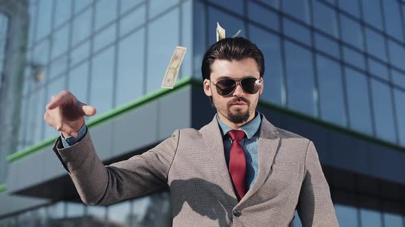 Rich Man in Modern Suit Wearing Sunglasses Throwing Money Up and Walking in the Street Near Office