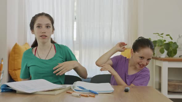 Two sisters fighting and laughing while preparing homework