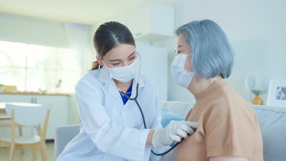 Asian doctor or nurse wear face mask give treatment to Senior elderly woman disabled patient.