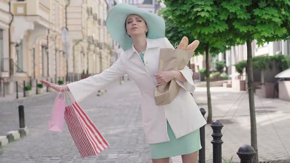 Elegant Stylish Caucasian Woman Hitchhiking on European City Street. Portrait of Confident Mid-adult