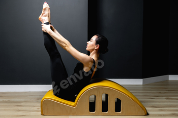 Fit woman doing pilates on arc barrel in fitness studio