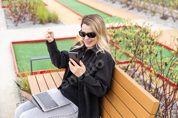 woman on golf course with smartphone with sports betting app