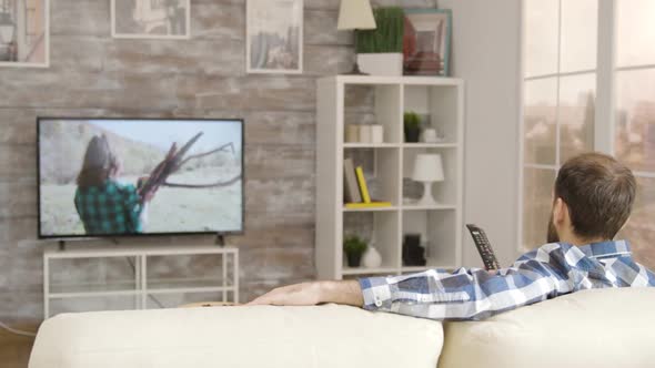 Back View Man Sitting on Sofa Changing Tv Channels