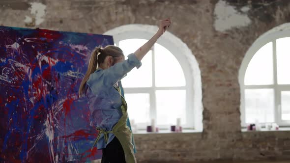 Female Artist Emotionally Dancing in Front of Abstract Painting in Studio in Slowmo