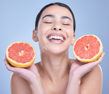 A  happy mixed race woman holding a grapefruit. Hispanic model promoting the skin benefits of citru