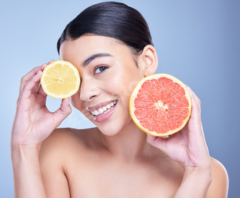 Portrait of a happy mixed race woman holding a lemon and grapefruit. Hispanic model promoting the s